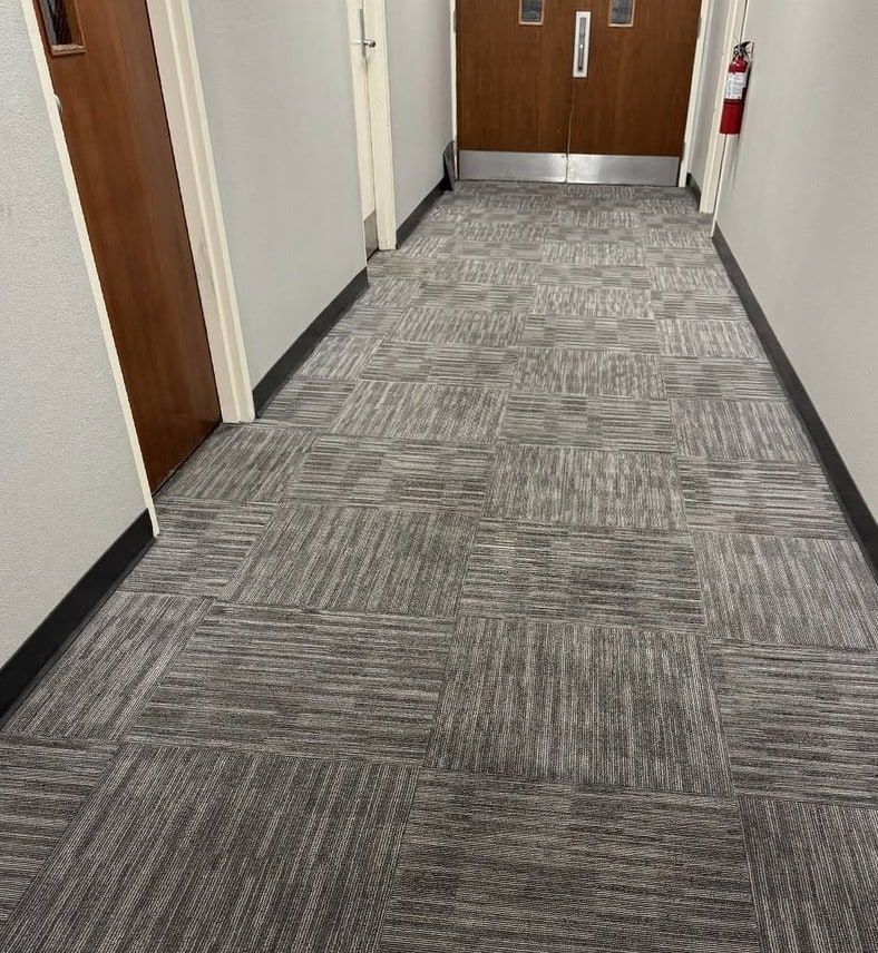 The same hallway carpet tiles even and clean, with the traffic lane gone