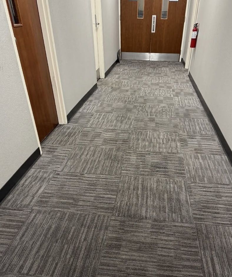 The same hallway carpet tiles even and clean, with the traffic lane gone