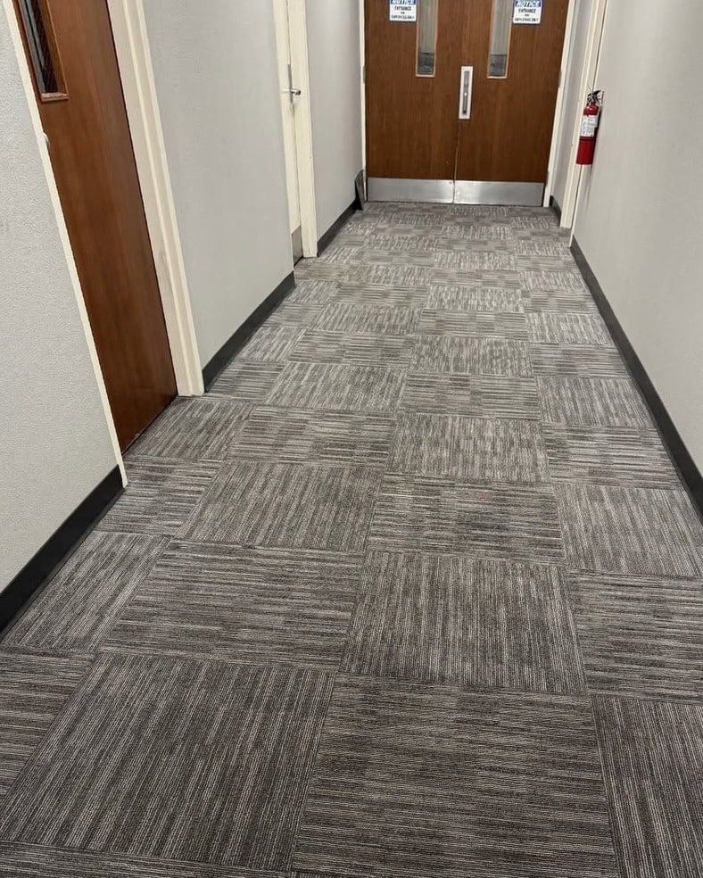 The same hallway carpet tiles even and clean, with the traffic lane gone
