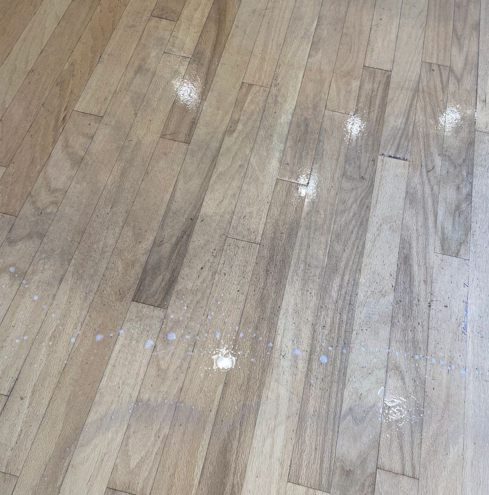 Dull, spotted oak hardwood floor with white residue before cleaning