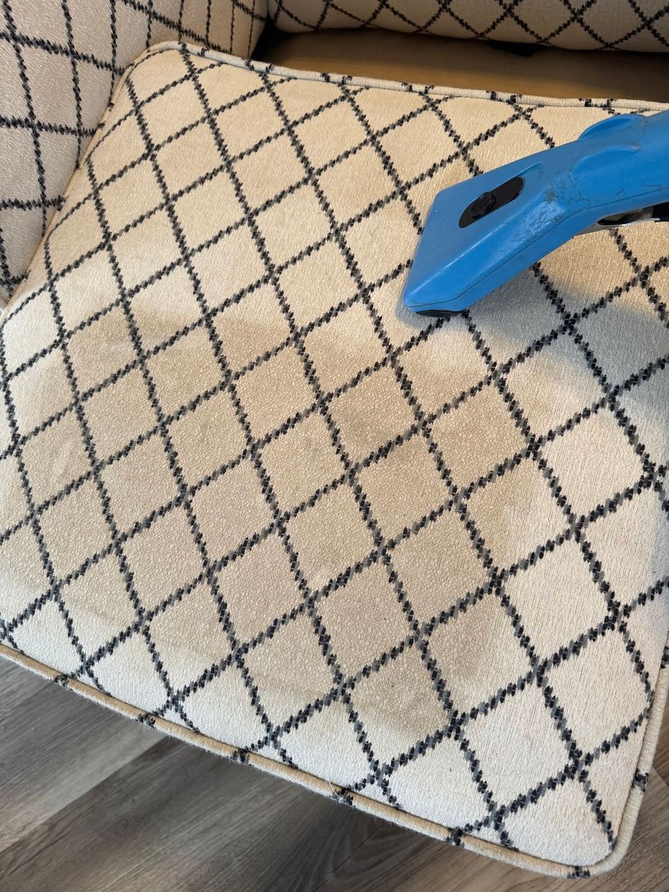 Mark's upholstery tool partway across a cream chair cushion with a navy lattice pattern