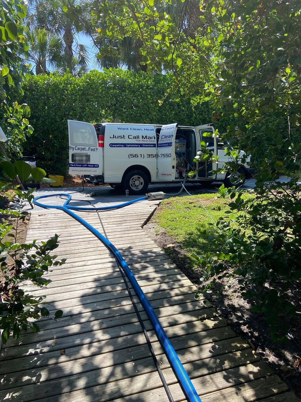Mark's truck-mount van parked at a job with its doors open and the cleaning hose running up the walkway to the house