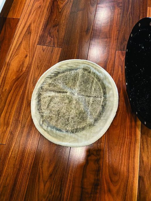 A white floor machine pad turned over on a walnut floor, gray with the dirt it lifted off the hardwood